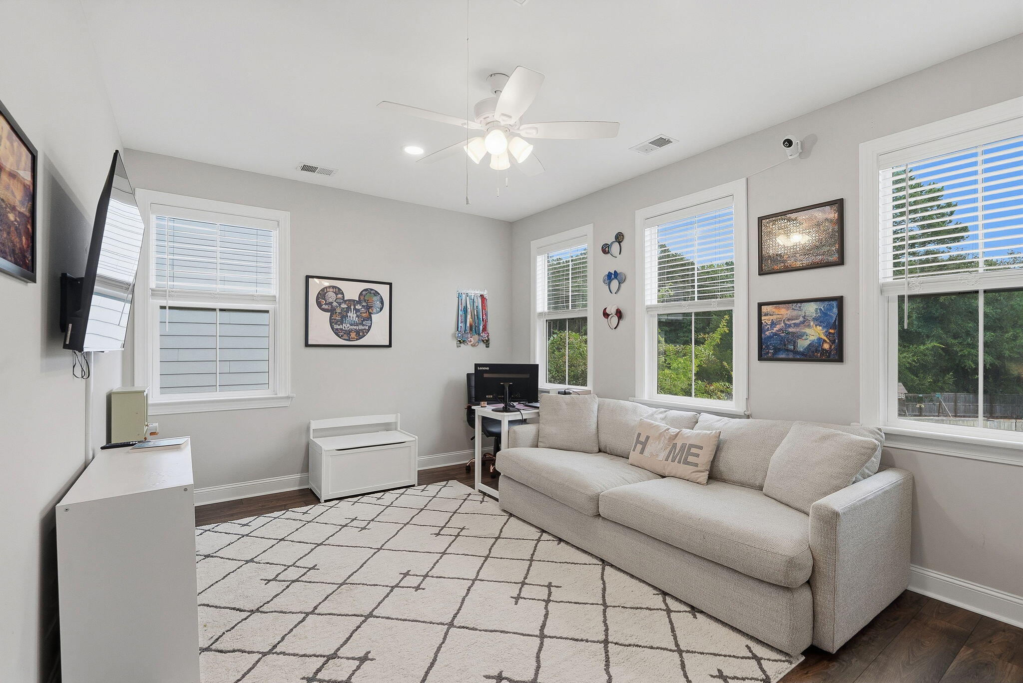 Furnished sitting room with a light sectional sofa, geometric rug, and windows overlooking greenery.