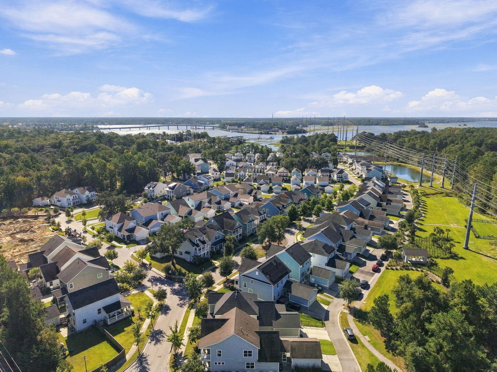 Aerial view of a coastal neighborhood, with tree-lined streets, waterways, and a bridge in the distance.
