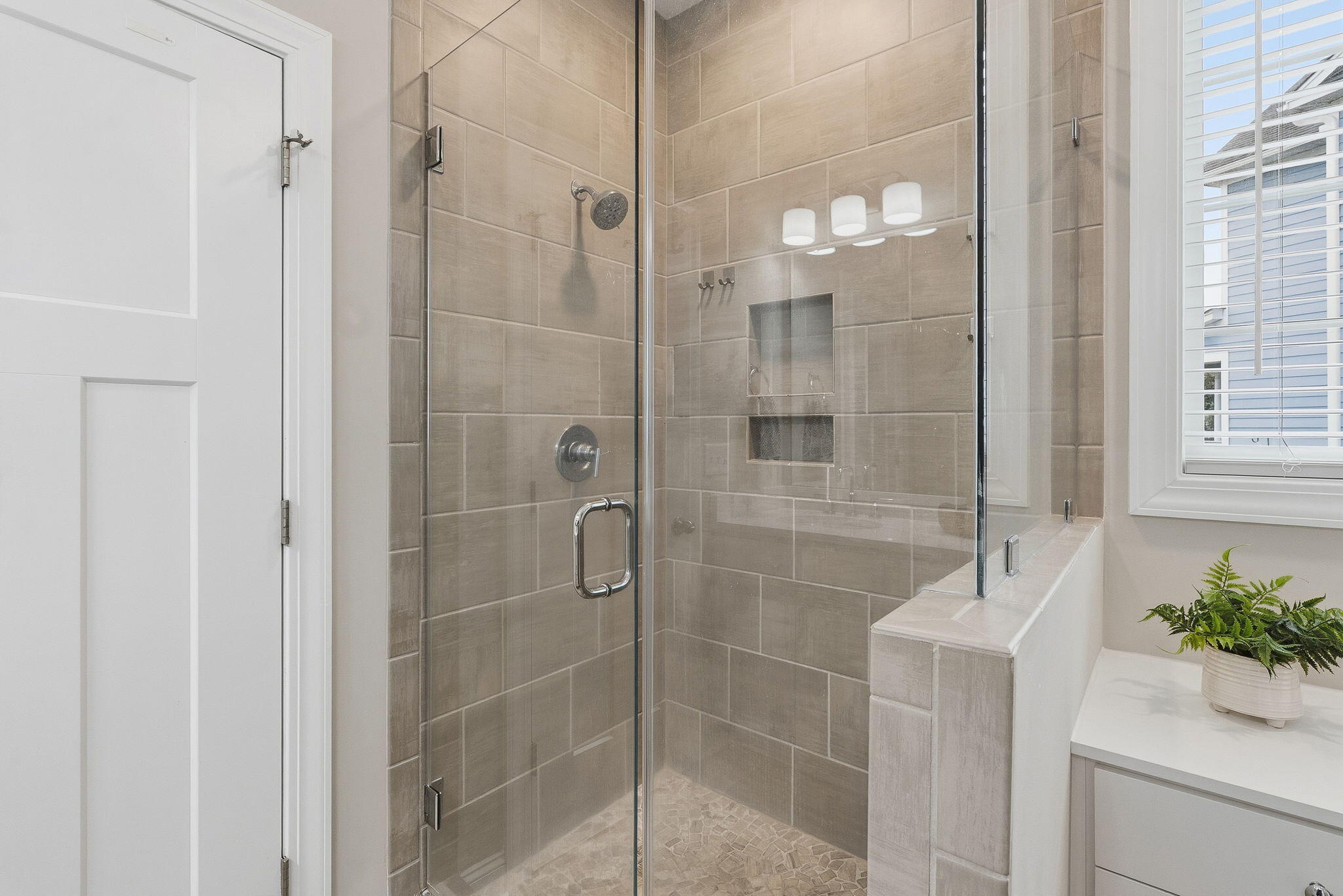 Bathroom with a glass-enclosed tiled shower, built-in niches, and a pebble mosaic floor.