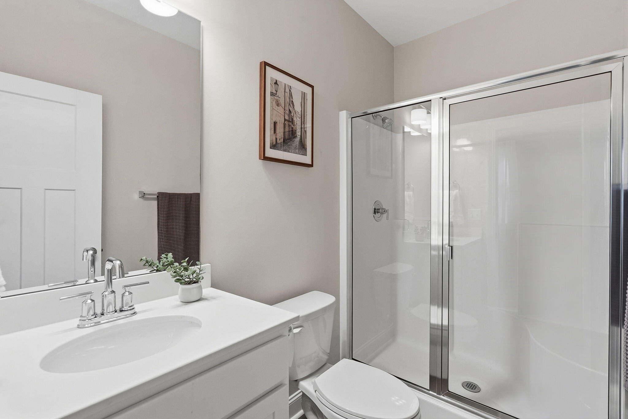 Bathroom with a white vanity, toilet, and glass-enclosed shower.