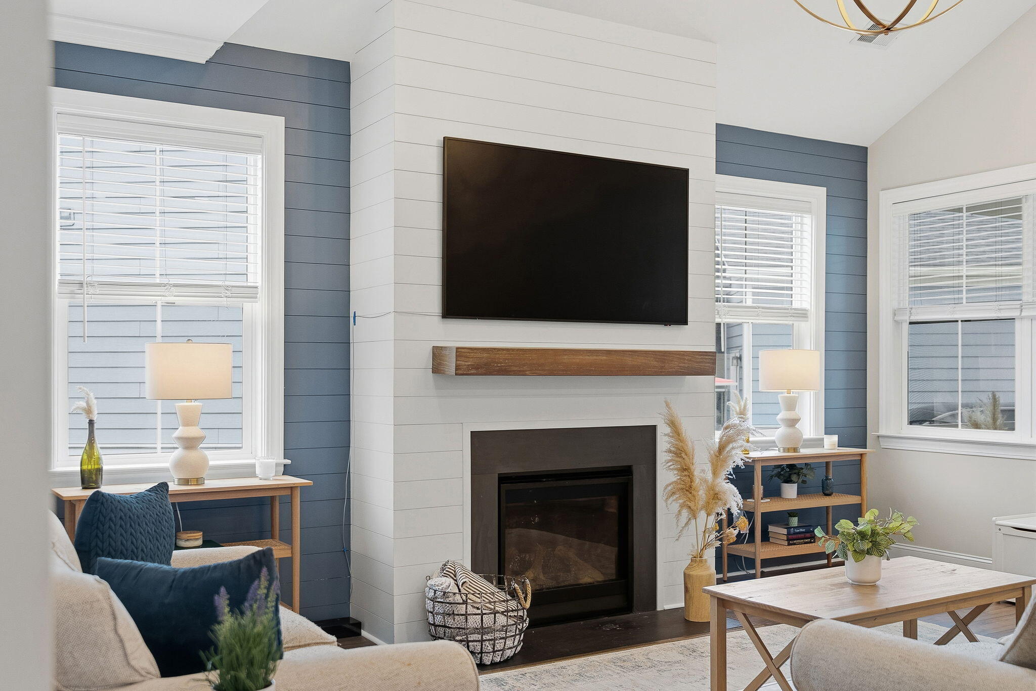 Staged living room with a shiplap fireplace, mounted television, and blue accent walls.