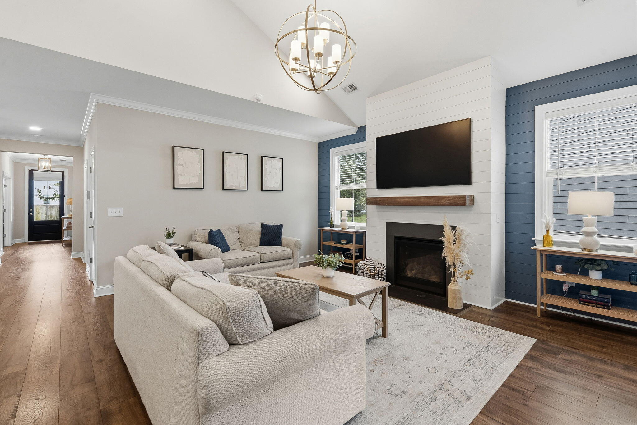 Living room with light sofas, a white shiplap fireplace wall, mounted TV, and navy-blue accent walls.