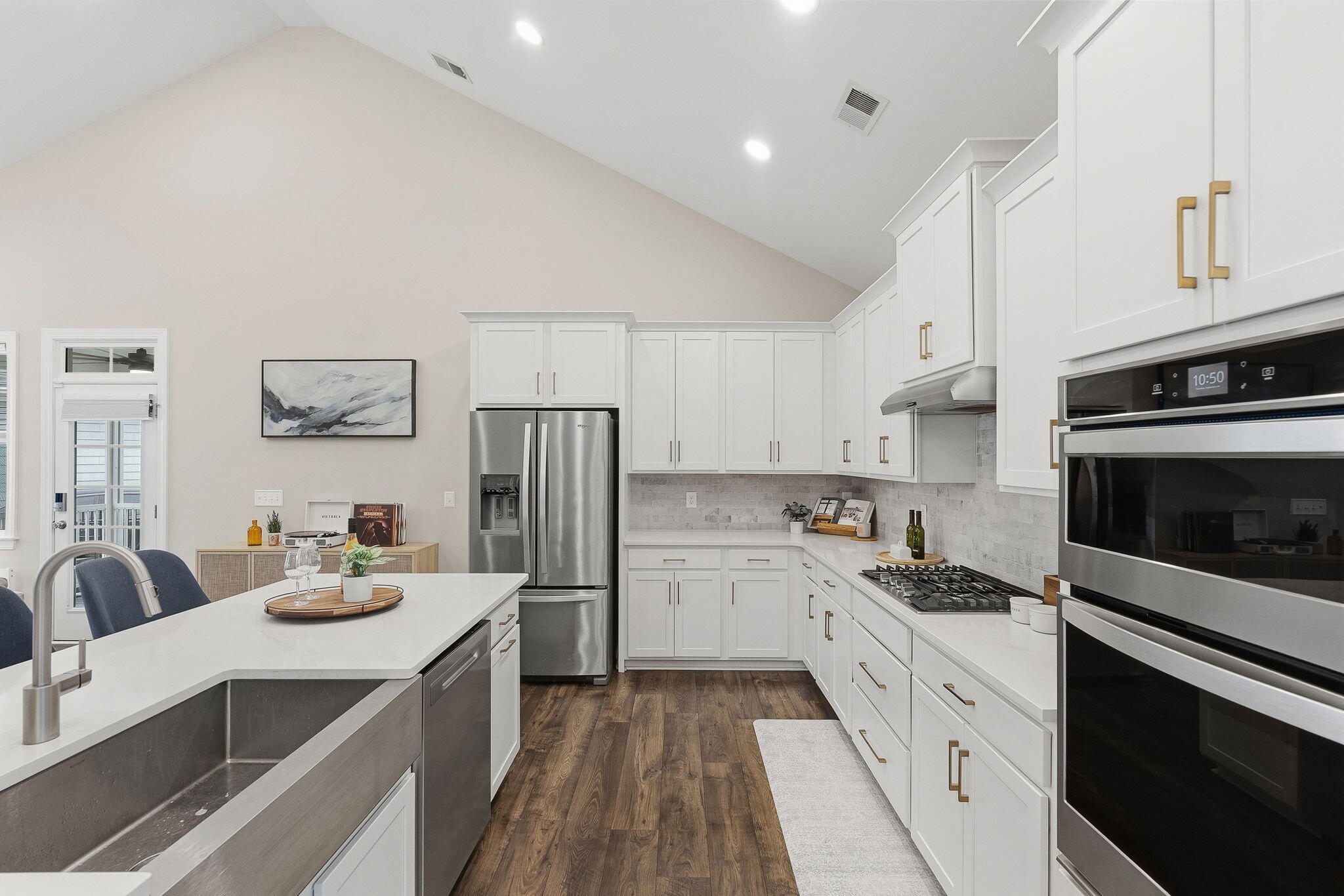 Kitchen with white cabinets, stainless steel appliances, farmhouse sink, and large island.