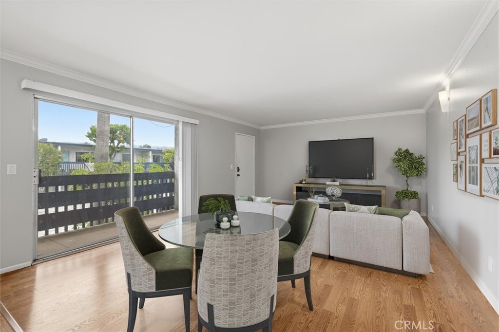 Living and dining area with a round glass table, sectional sofa, and sliding glass door to a balcony.