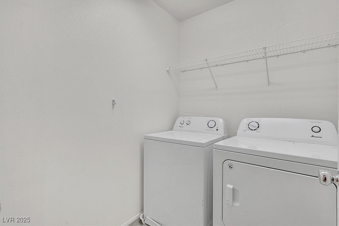 Laundry room with a white washer and dryer beneath a long wire shelf.