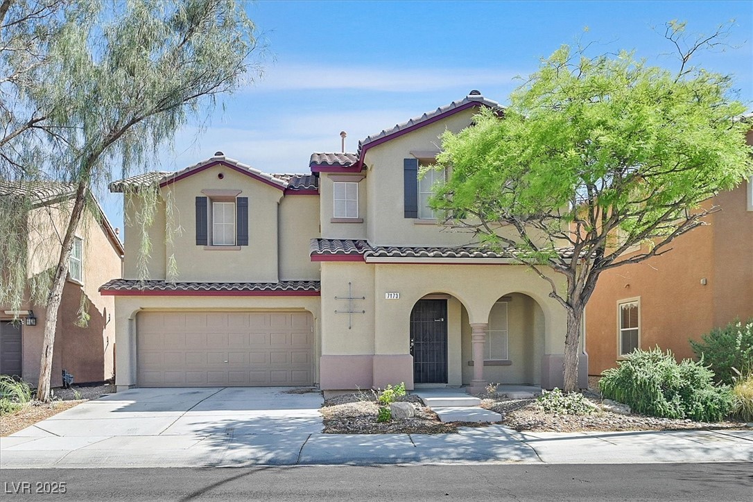 Two-story stucco home with a tile roof, double garage, and arched entry porch.
