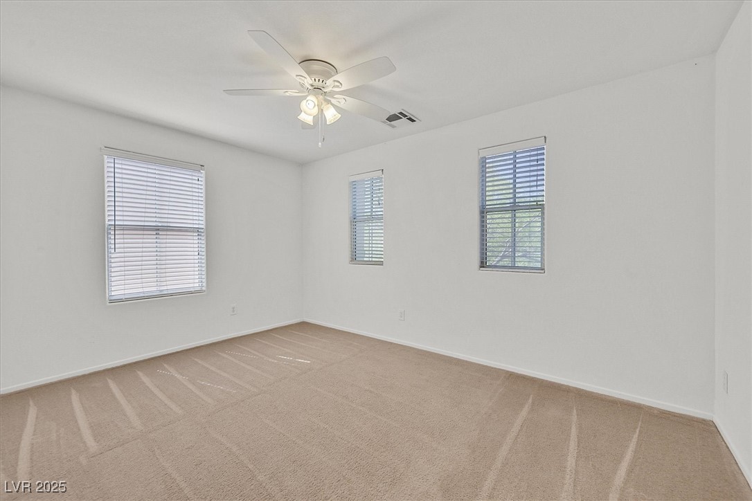 Vacant carpeted bedroom with three blinded windows and a ceiling fan.