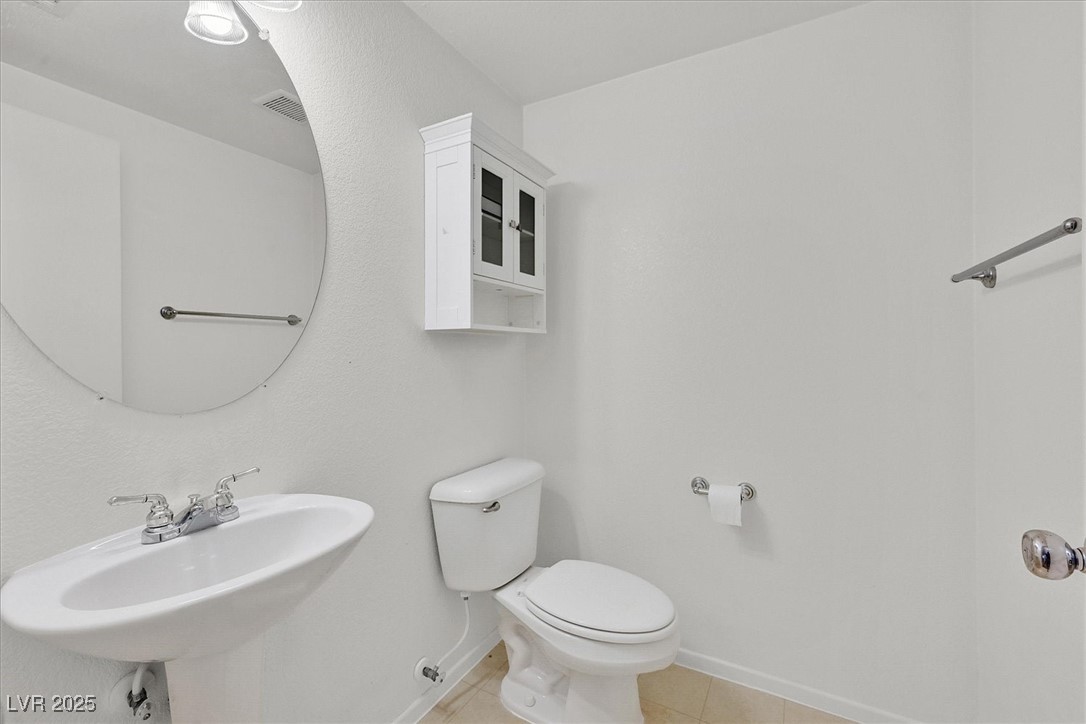 Bathroom with a pedestal sink, round mirror, toilet, and wall-mounted cabinet.