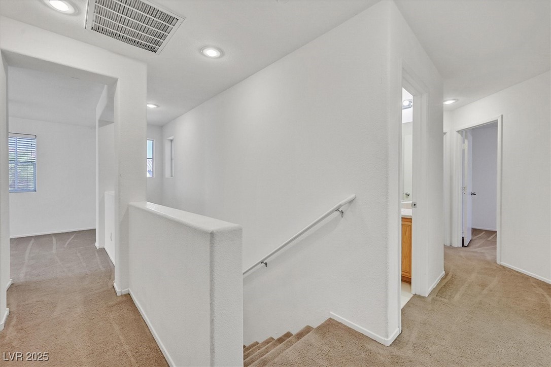 Carpeted stair landing with a white handrail and open doorways to adjacent rooms.