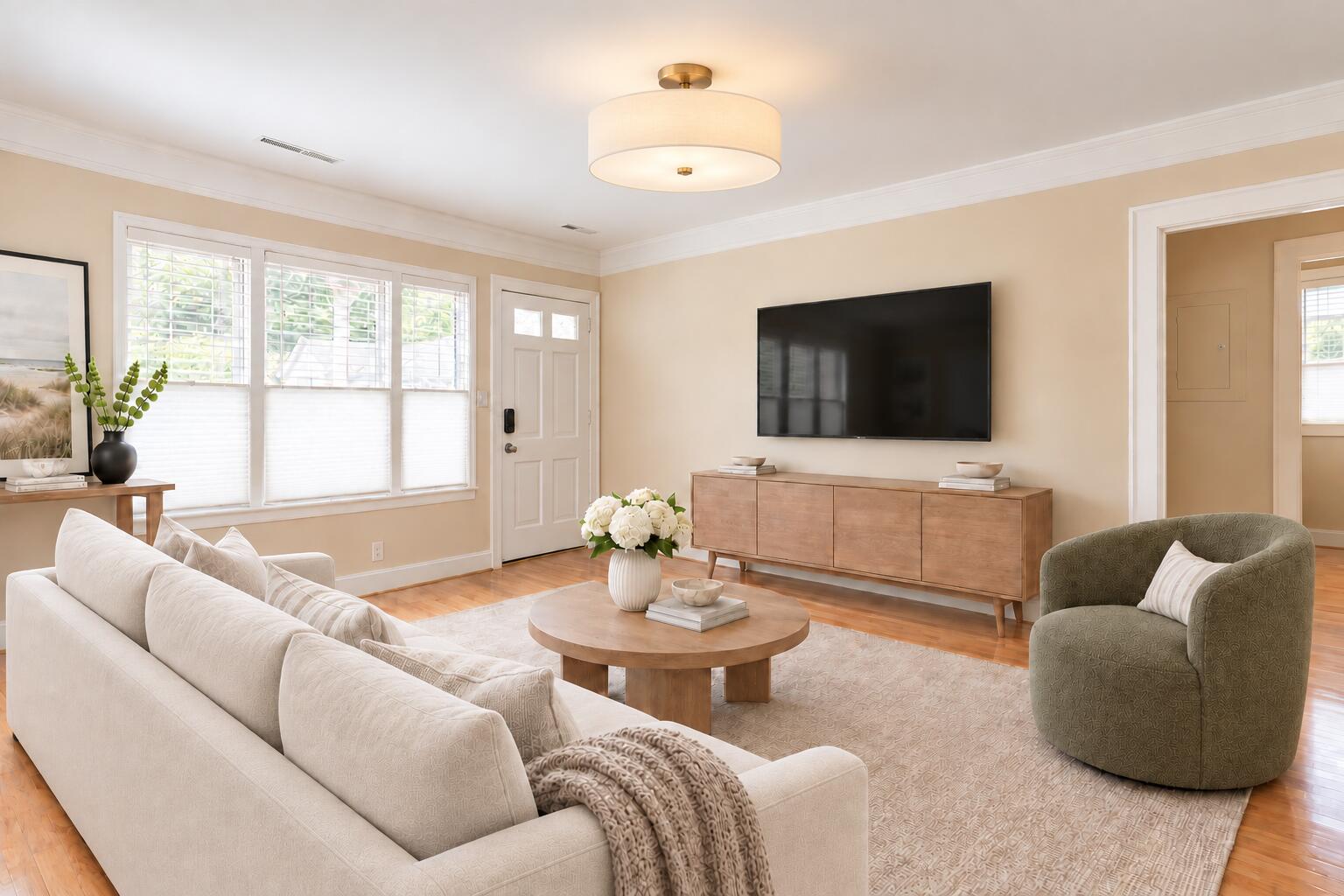 Staged living room with a cream sofa, green armchair, and wall-mounted television.