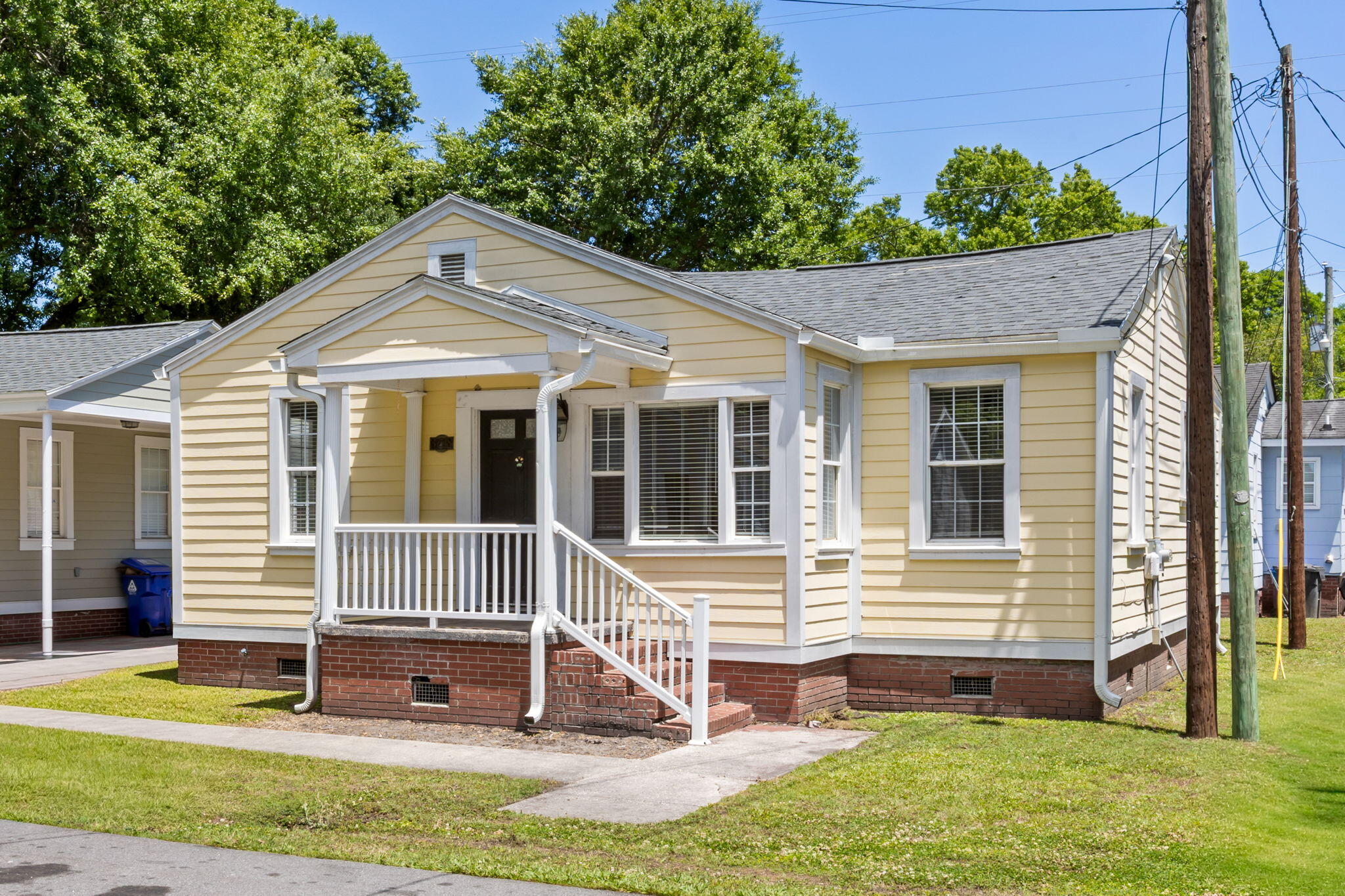 Pale yellow house with white trim, a covered front porch, front steps, and a brick foundation.