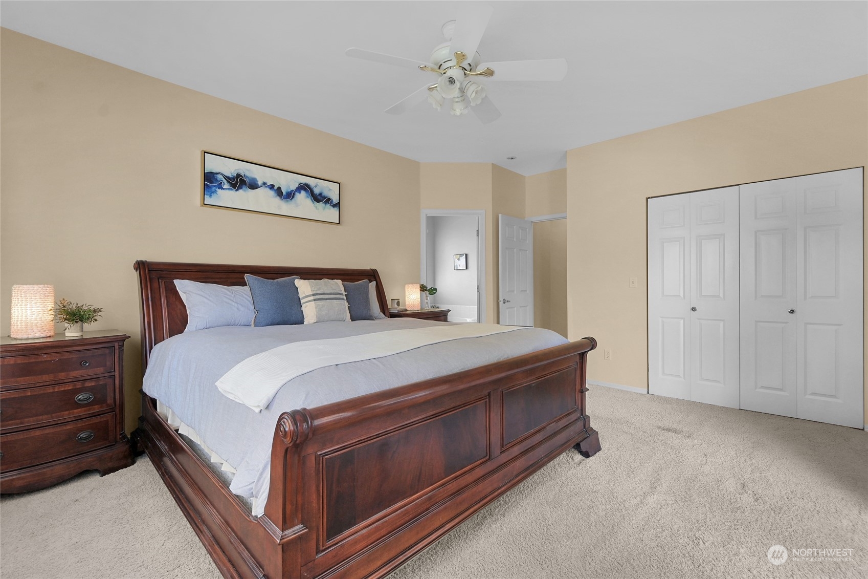 Staged bedroom with a dark wood bed, pale blue bedding, and double-door closet.