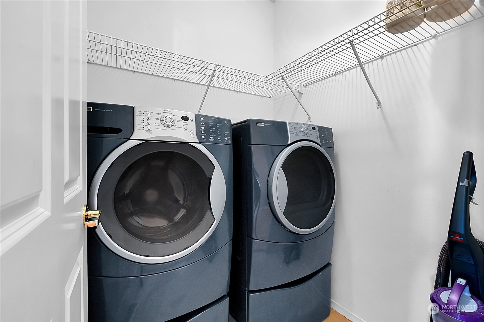 Laundry room with front-loading washer and dryer beneath wire shelving.