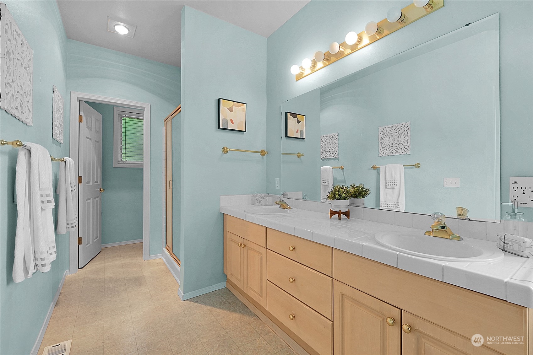 Bathroom with a double-sink vanity, large mirror, and glass shower enclosure.