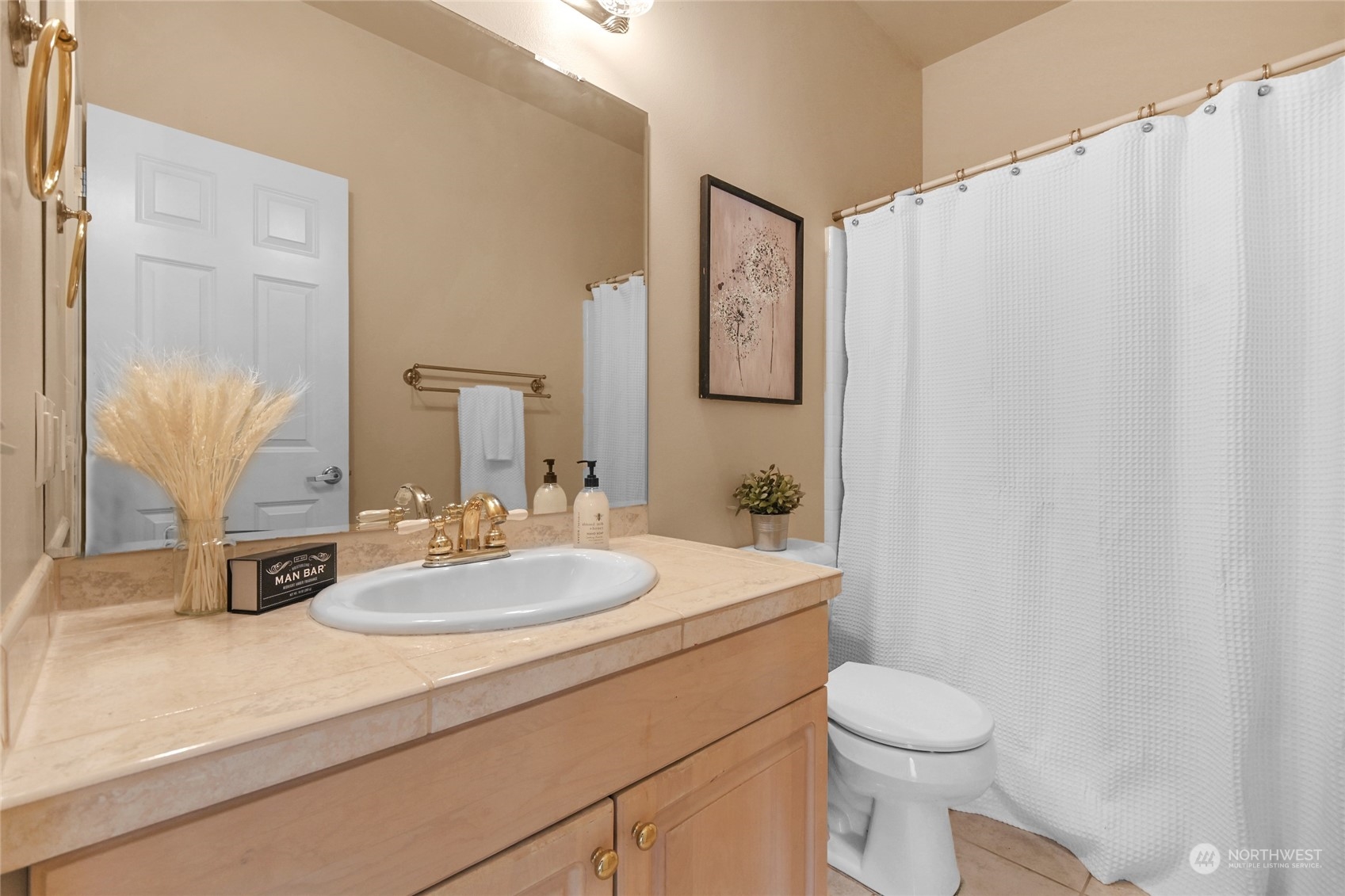 Bathroom with a wood vanity, oval sink, gold-tone faucet, and white shower curtain.