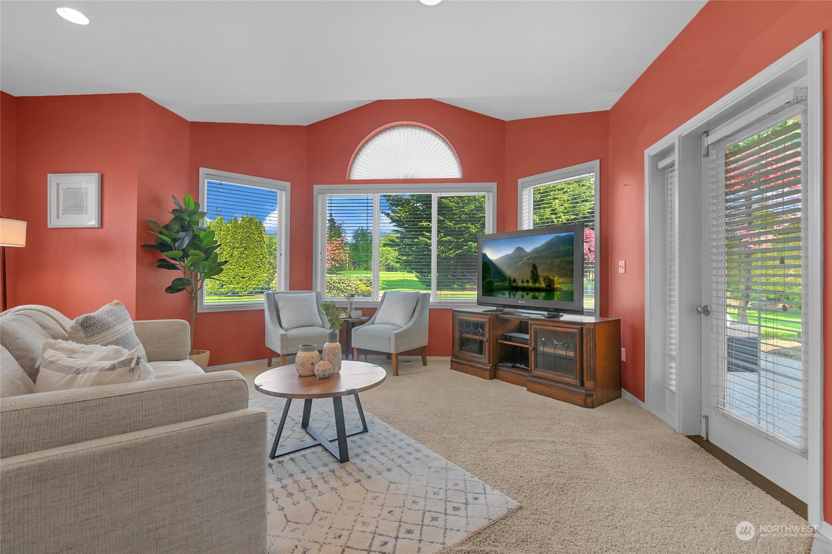 Living room with coral walls, bay windows, a semicircular fanlight, and garden views.