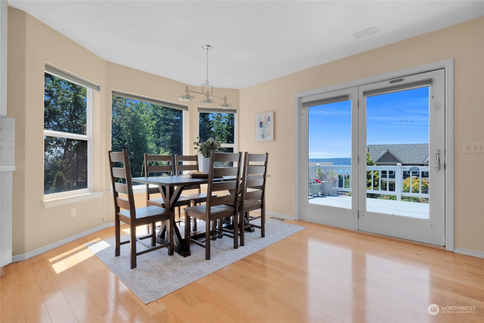 Dining room with a dark wood table, large windows, and water visible beyond the deck.