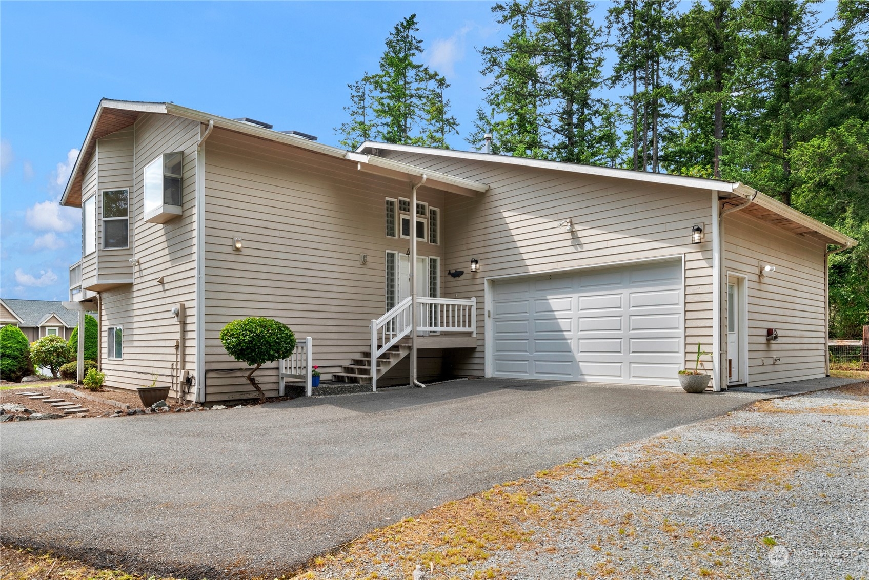Beige-sided home with a two-car garage, raised entry stairs, and a paved driveway.