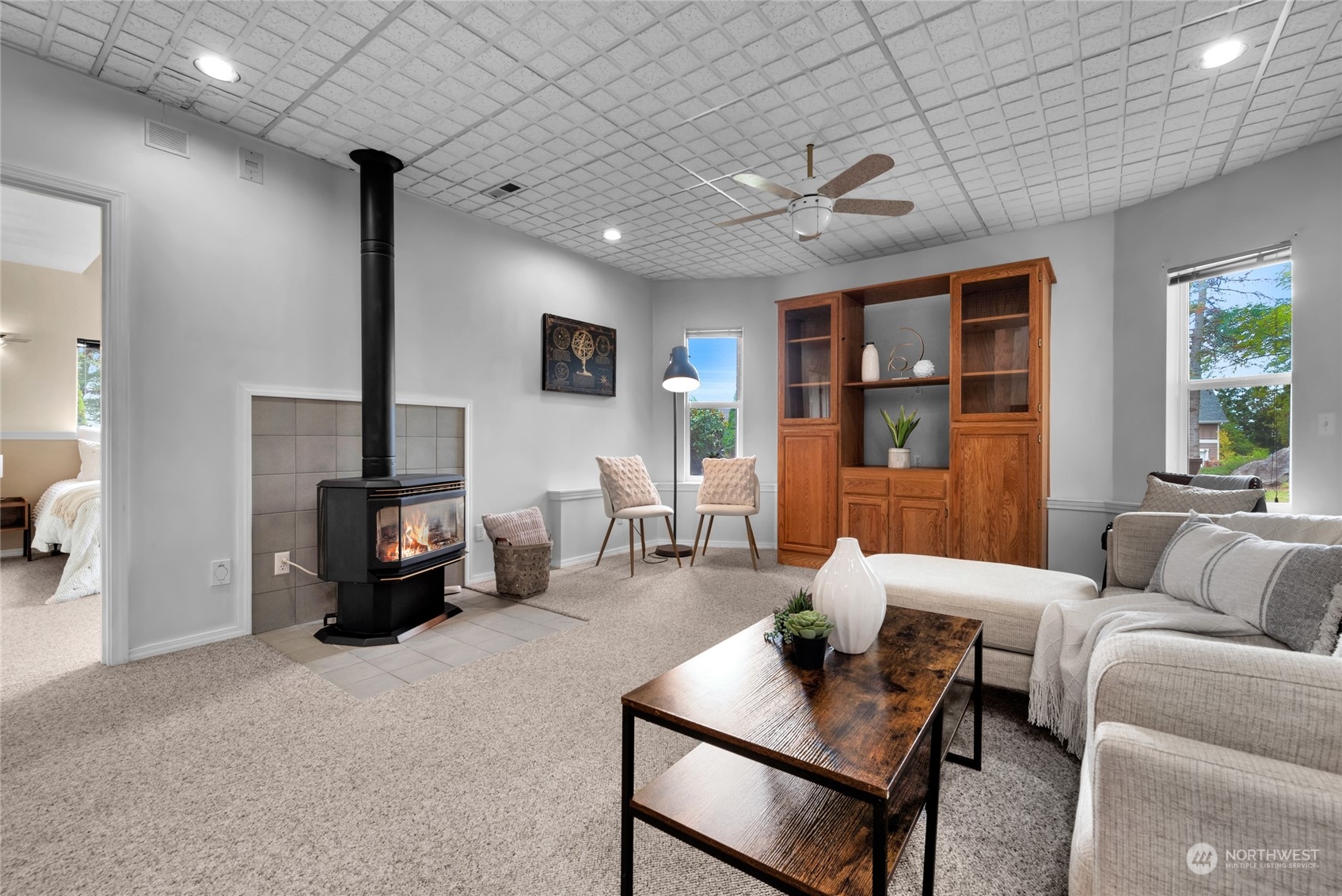 Furnished living room with a black wood-burning stove and built-in wooden cabinetry.