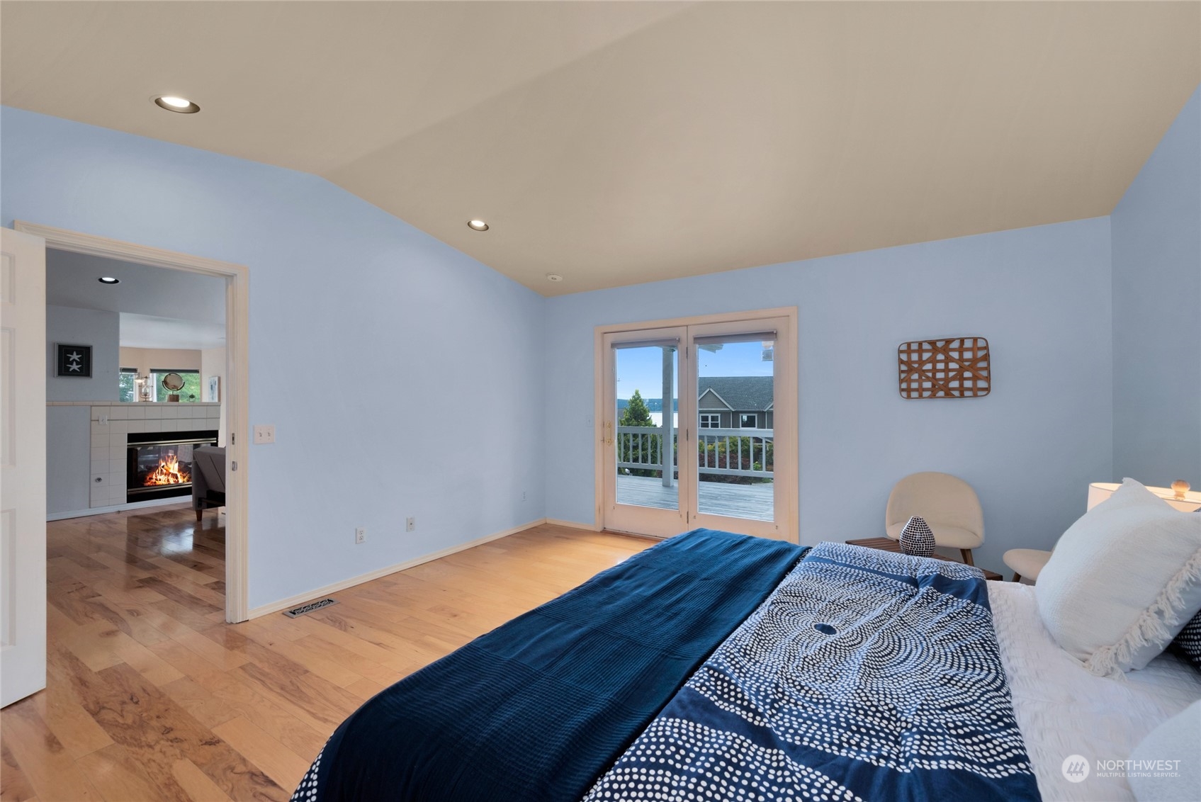 Bedroom with blue bedding and deck doors overlooking the water.