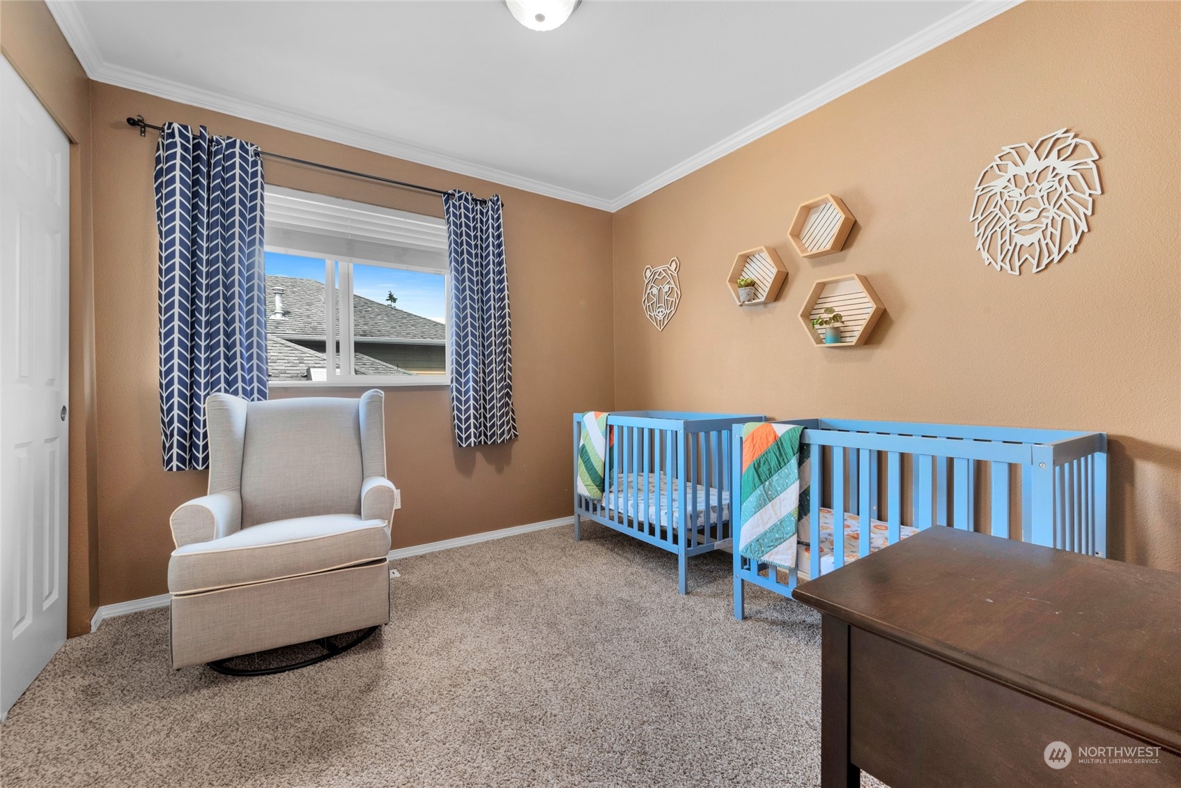 Nursery with two blue cribs, a beige rocking chair, and animal-themed wall decor.