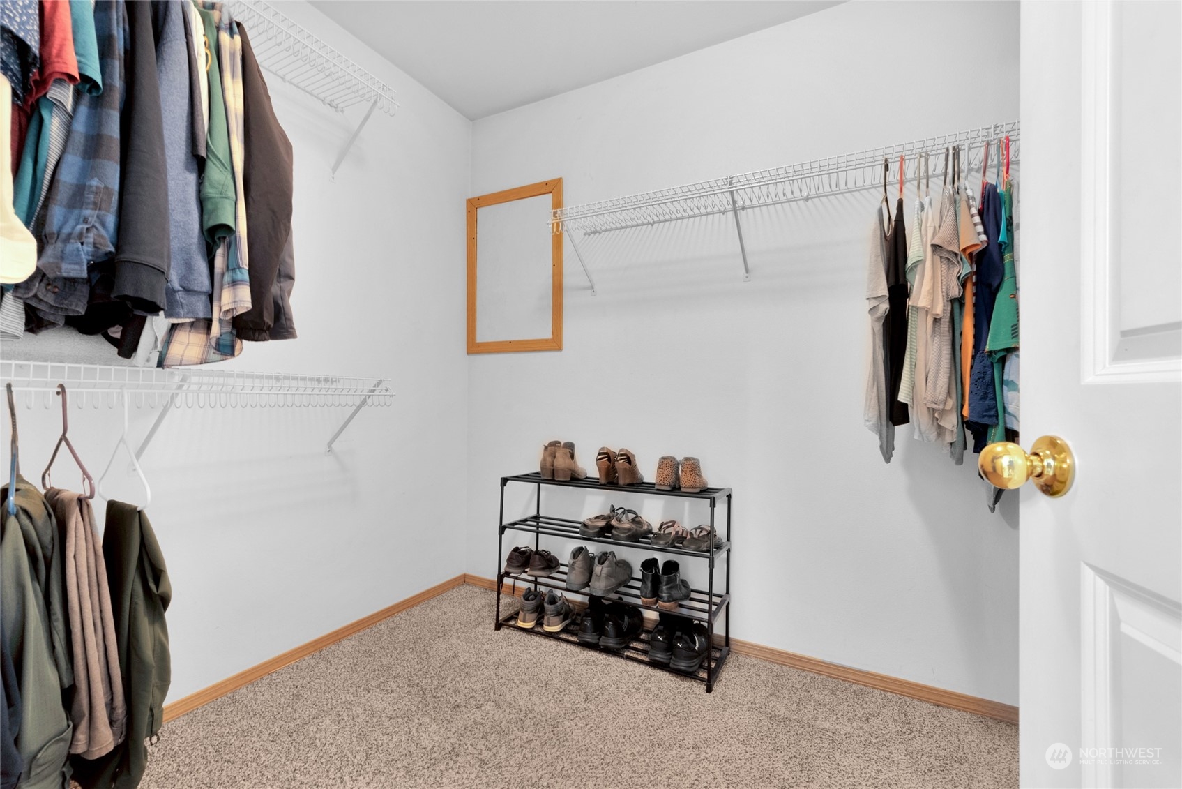 Walk-in closet with wire shelves, hanging clothes, and a freestanding shoe rack.