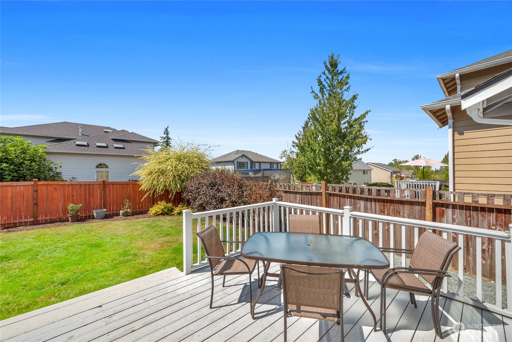 Backyard deck with white railings, patio dining set, and fenced lawn.