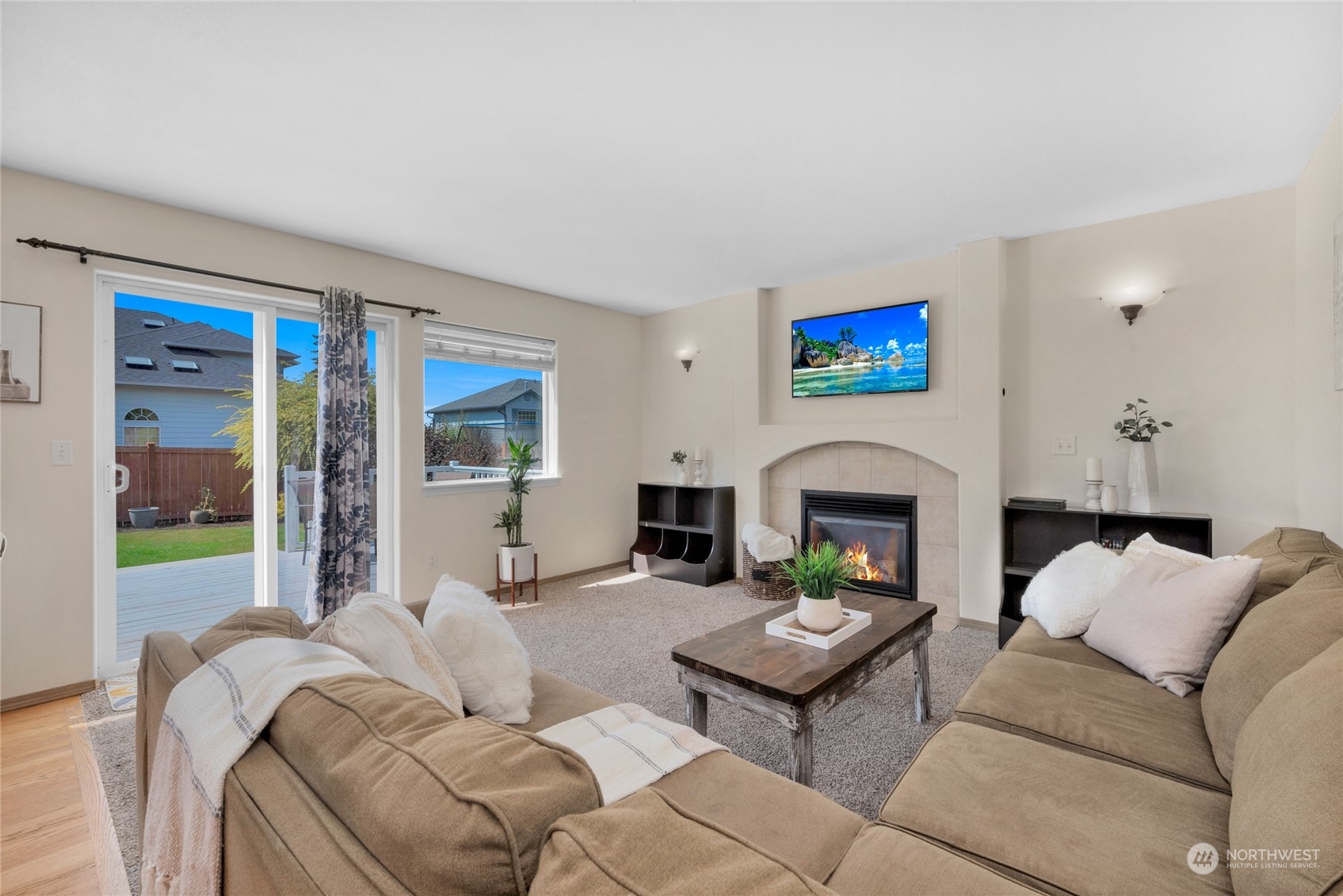 Living room with a tiled fireplace, beige sectional sofas, and sliding doors to a deck.
