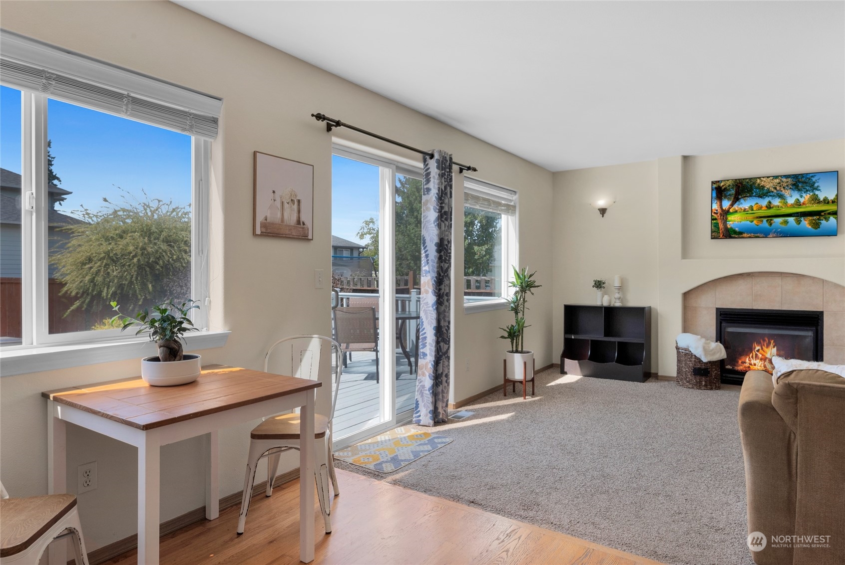 Living room with a tiled fireplace, large windows, and sliding glass door to a deck.