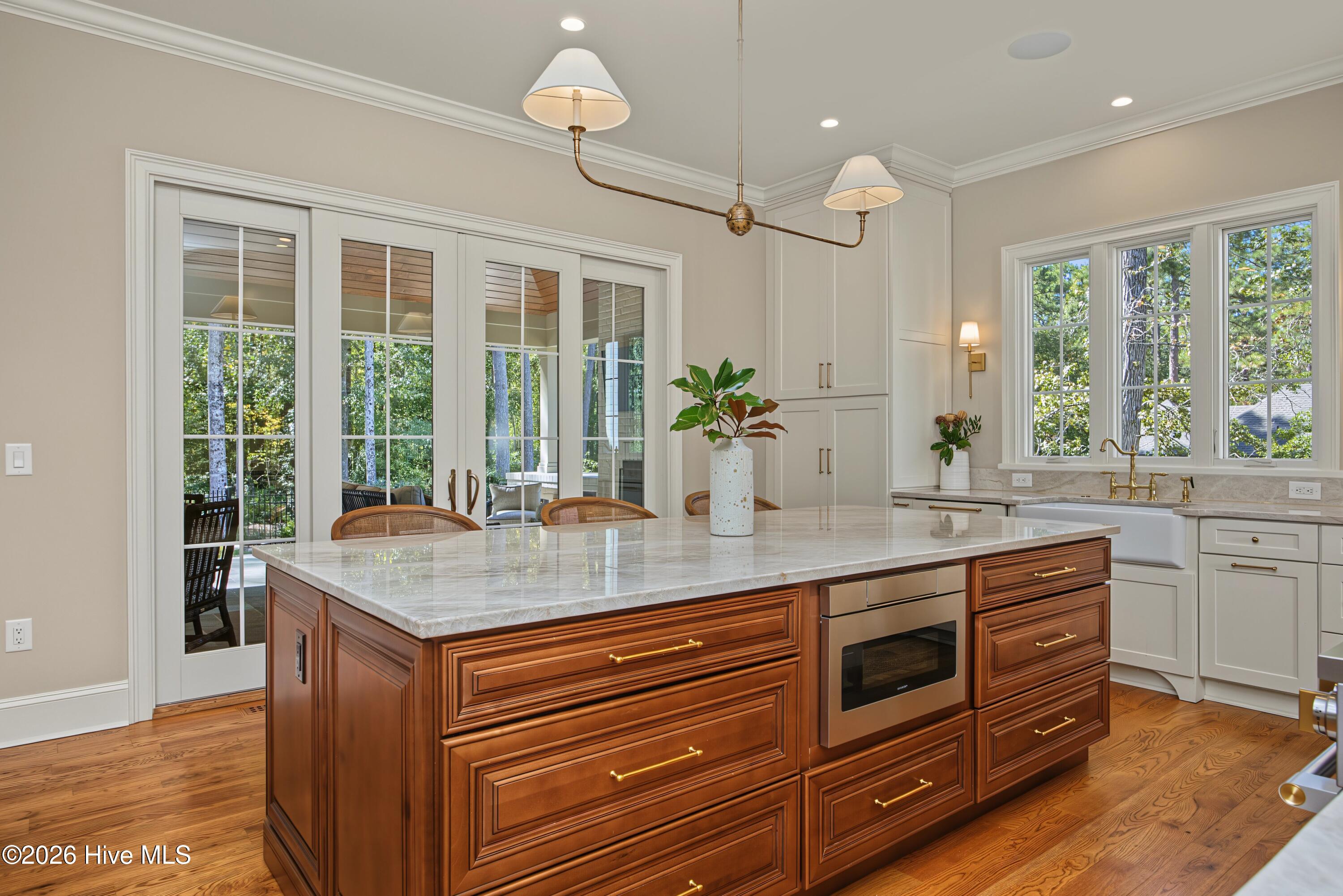 Kitchen with a marble-topped wood island, built-in oven, farmhouse sink, and windows overlooking trees.