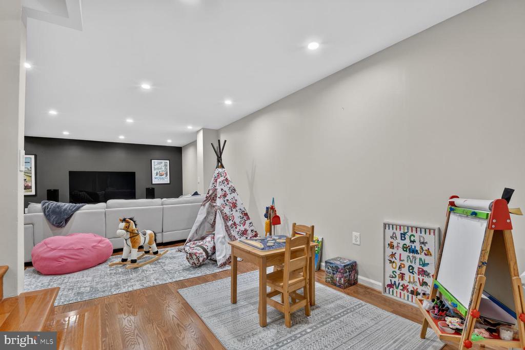 Playroom with a child-sized table, teepee, rocking horse, and adjoining family room.