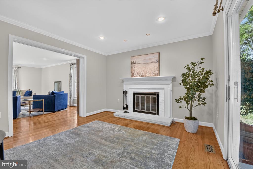 Living room with a white fireplace, gray rug, hardwood floors, and glass patio doors.