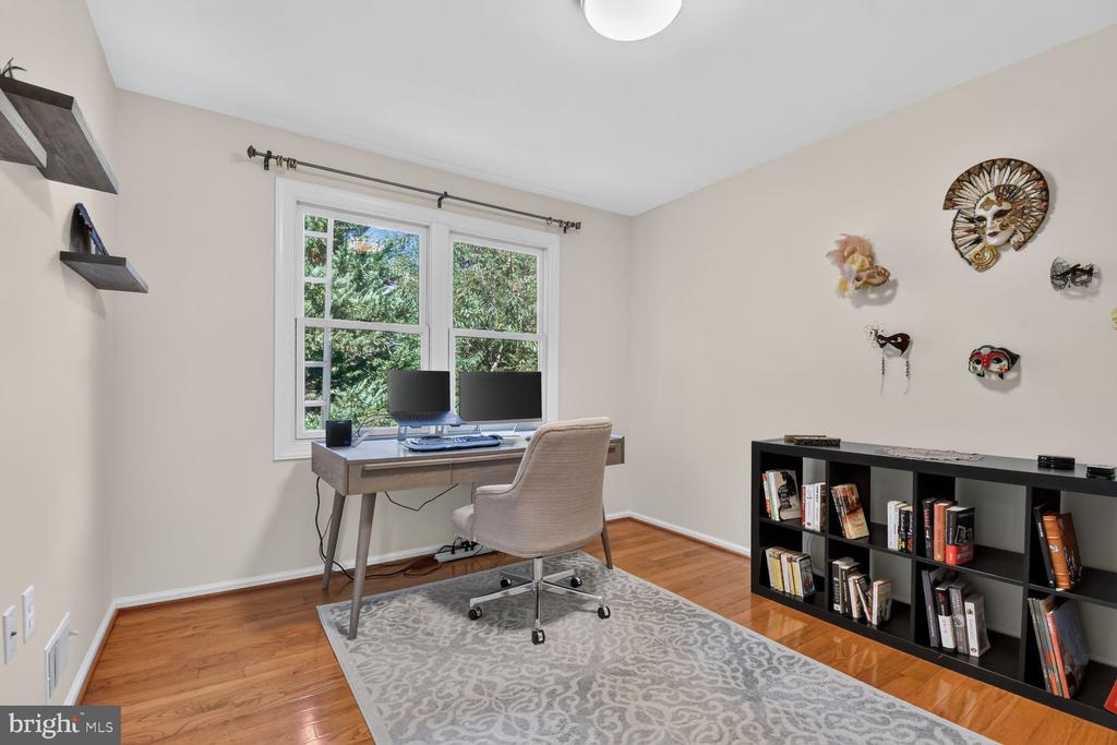 Home office with a desk, dual monitors, wall shelves, and a black bookcase.