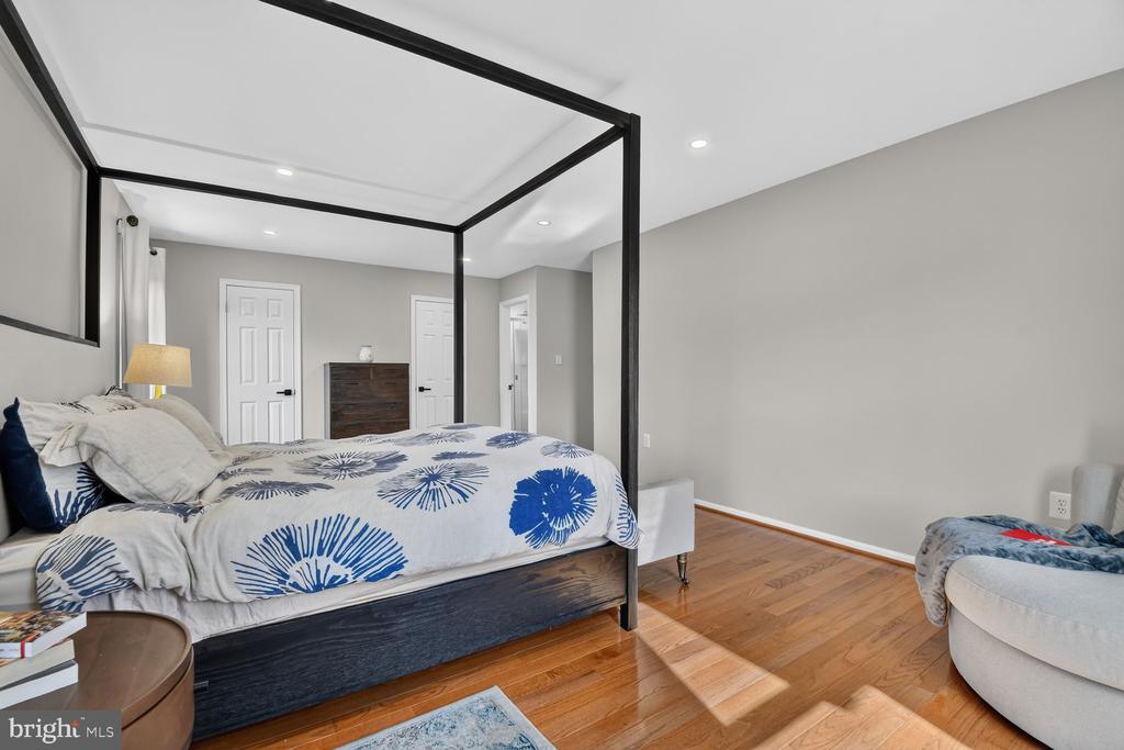 Bedroom with a black canopy bed, blue-and-white bedding, hardwood floors, and gray walls.