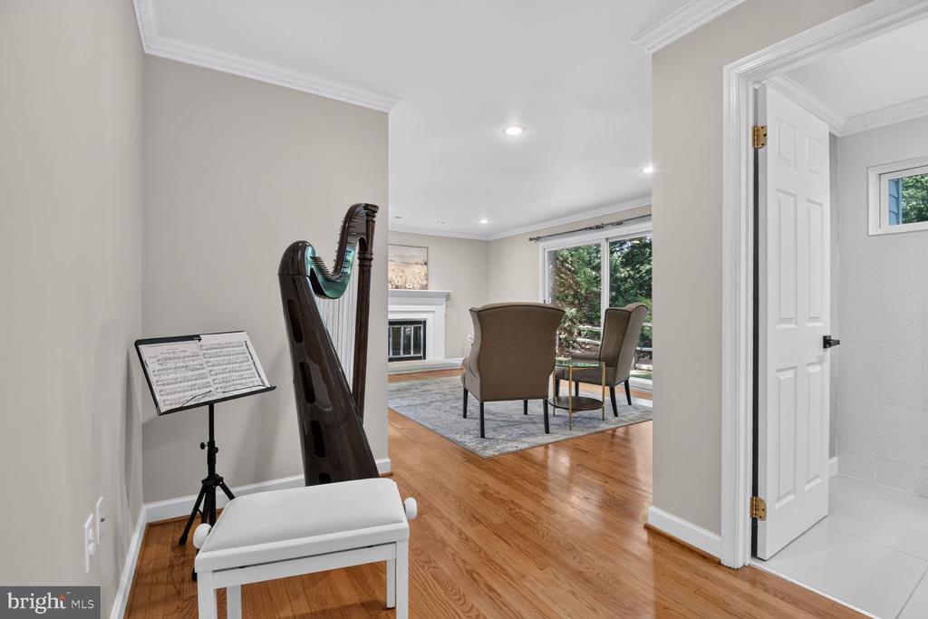 Music room with a harp and bench opening to a bright sitting area with a fireplace.