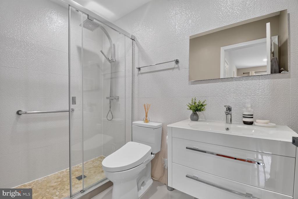 Modern bathroom with a glass shower, pebble-tile floor, and wide white vanity.