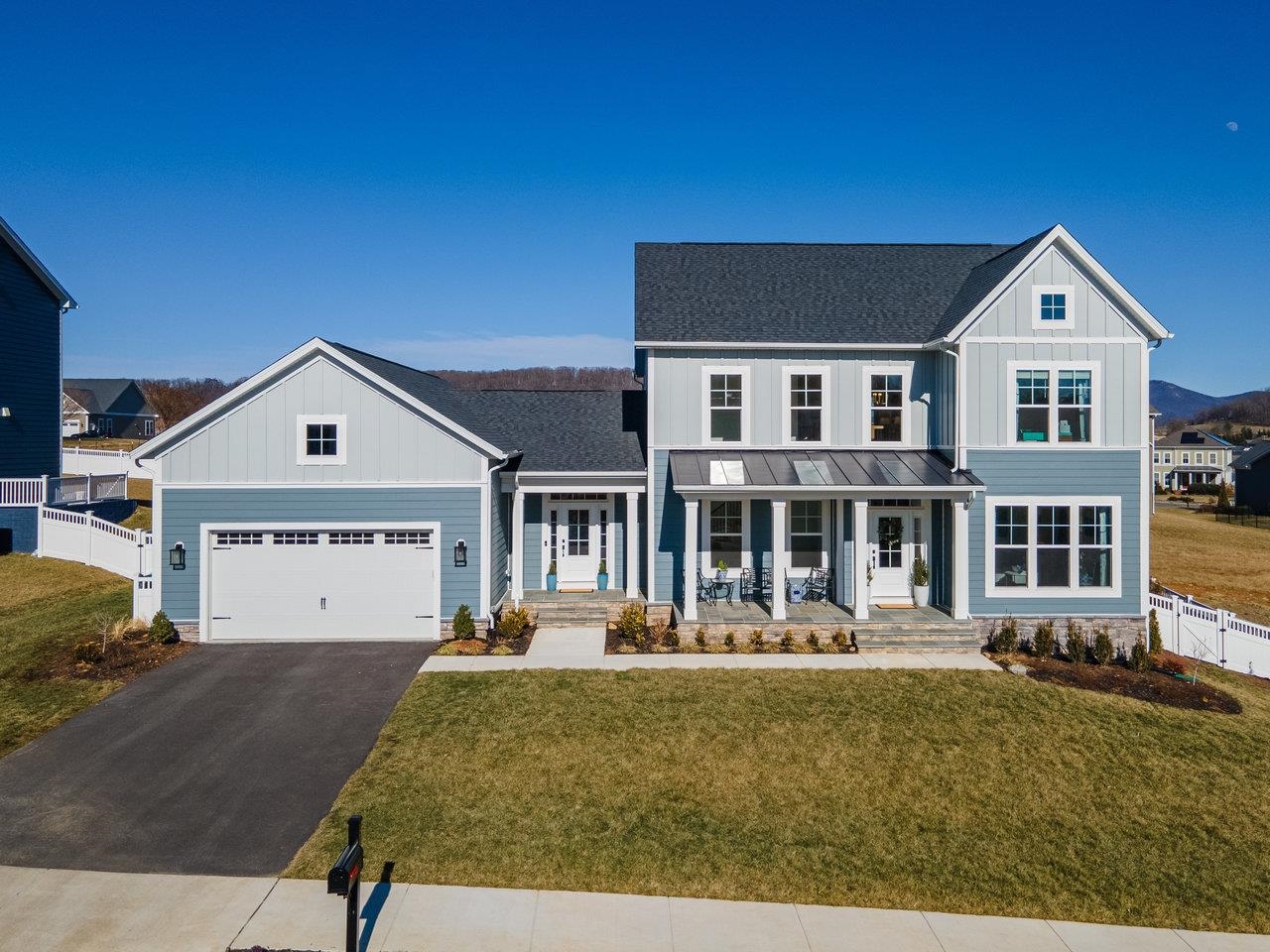 Blue-gray two-story house with a large garage, covered porch, and distant mountain views.