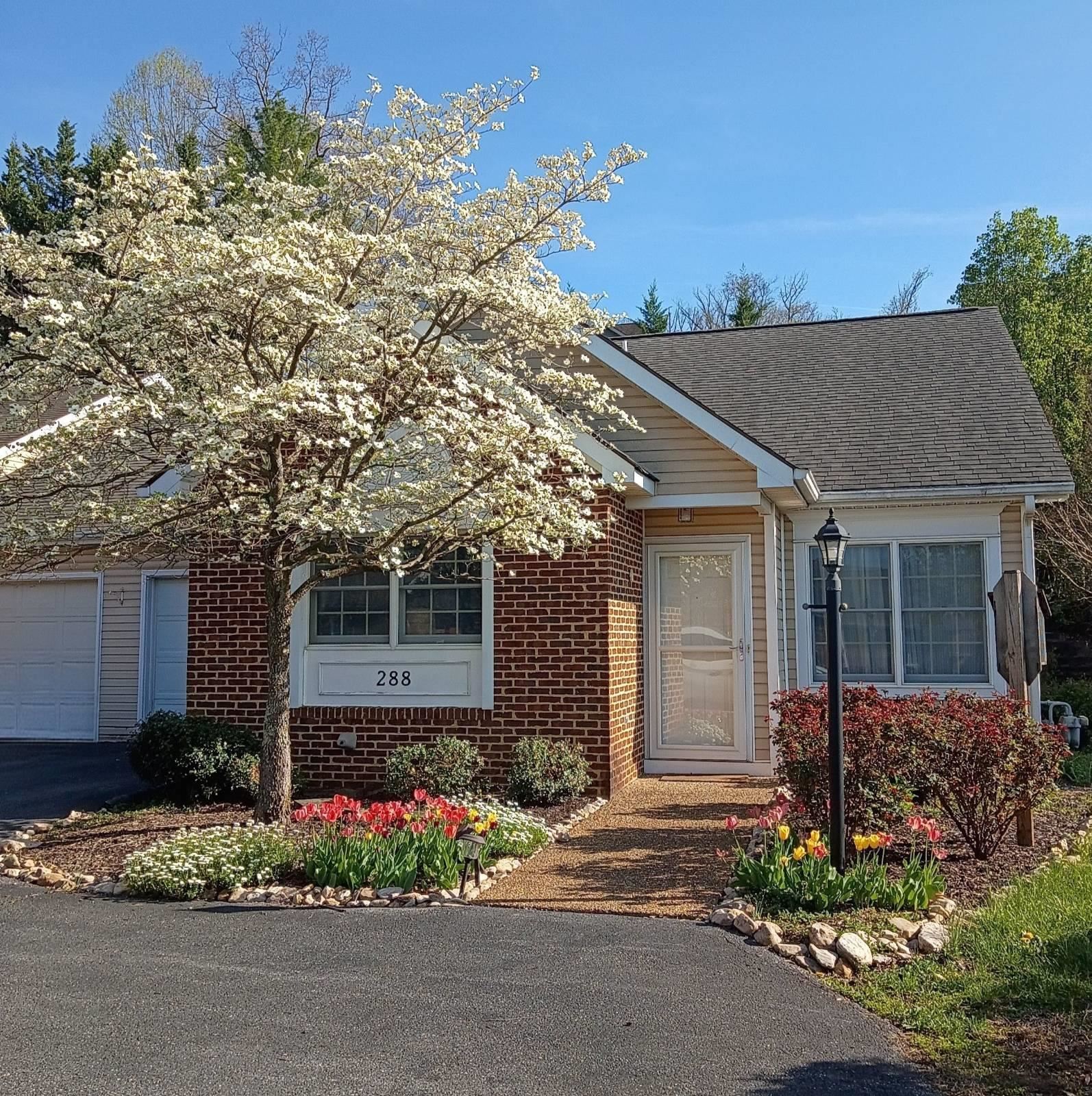 Brick-and-siding home with a flowering tree and tulip garden by the front entrance.