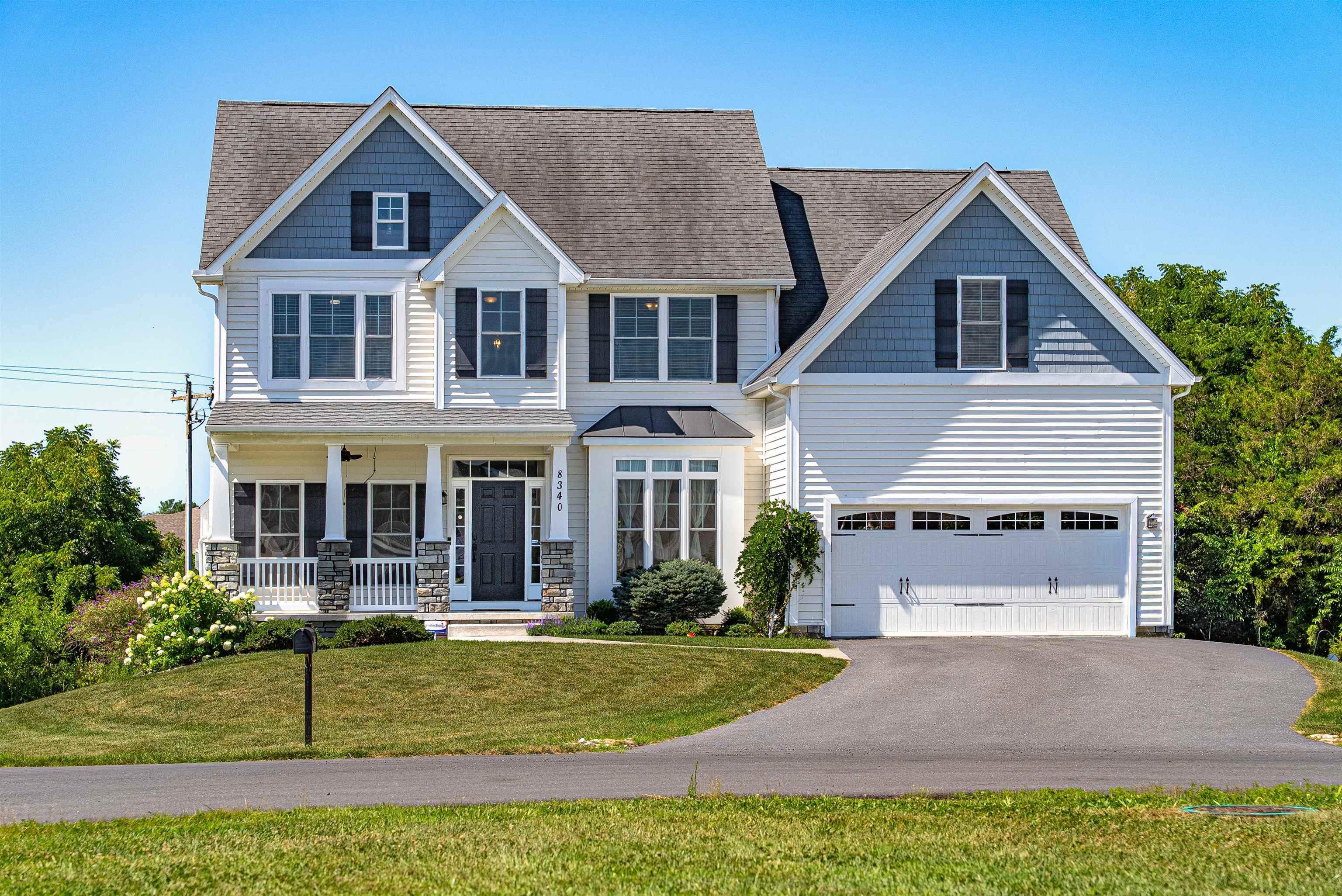 Two-story house with blue-gray gables, a covered porch, and an attached two-car garage.