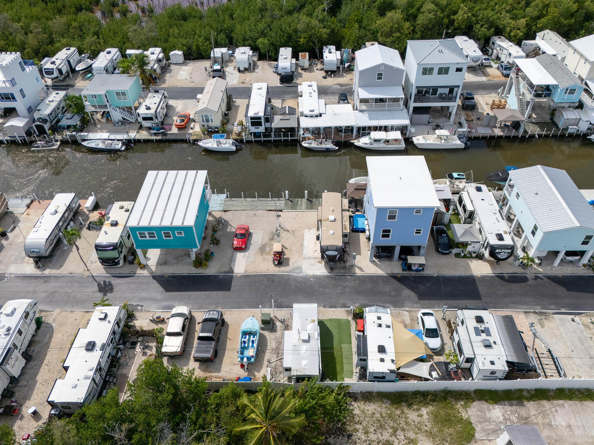 Waterfront RV community beside a canal, with small homes, trailers, and boats along the docks.