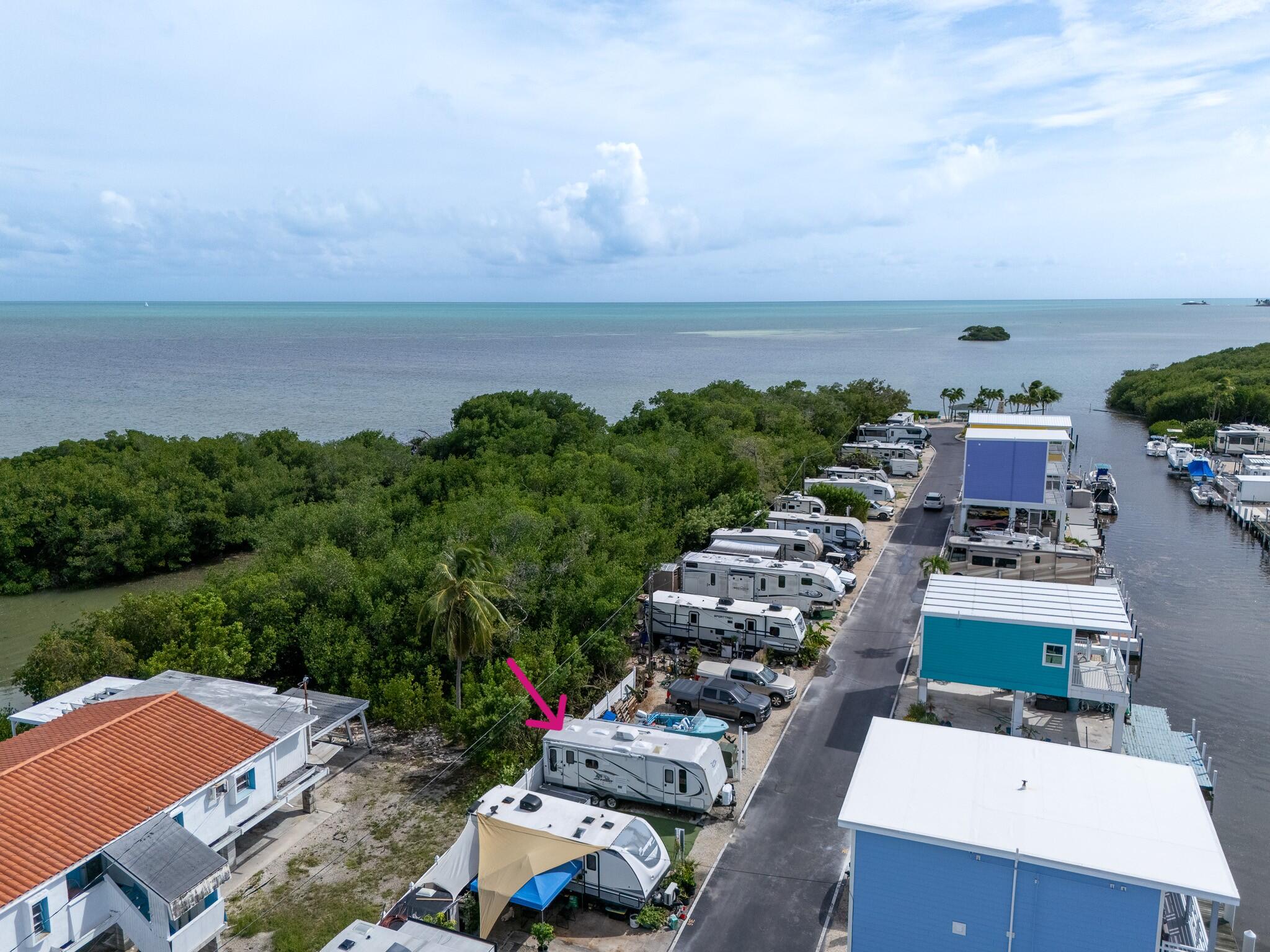 Waterfront RV park with a marked motorhome beside mangroves and open water.