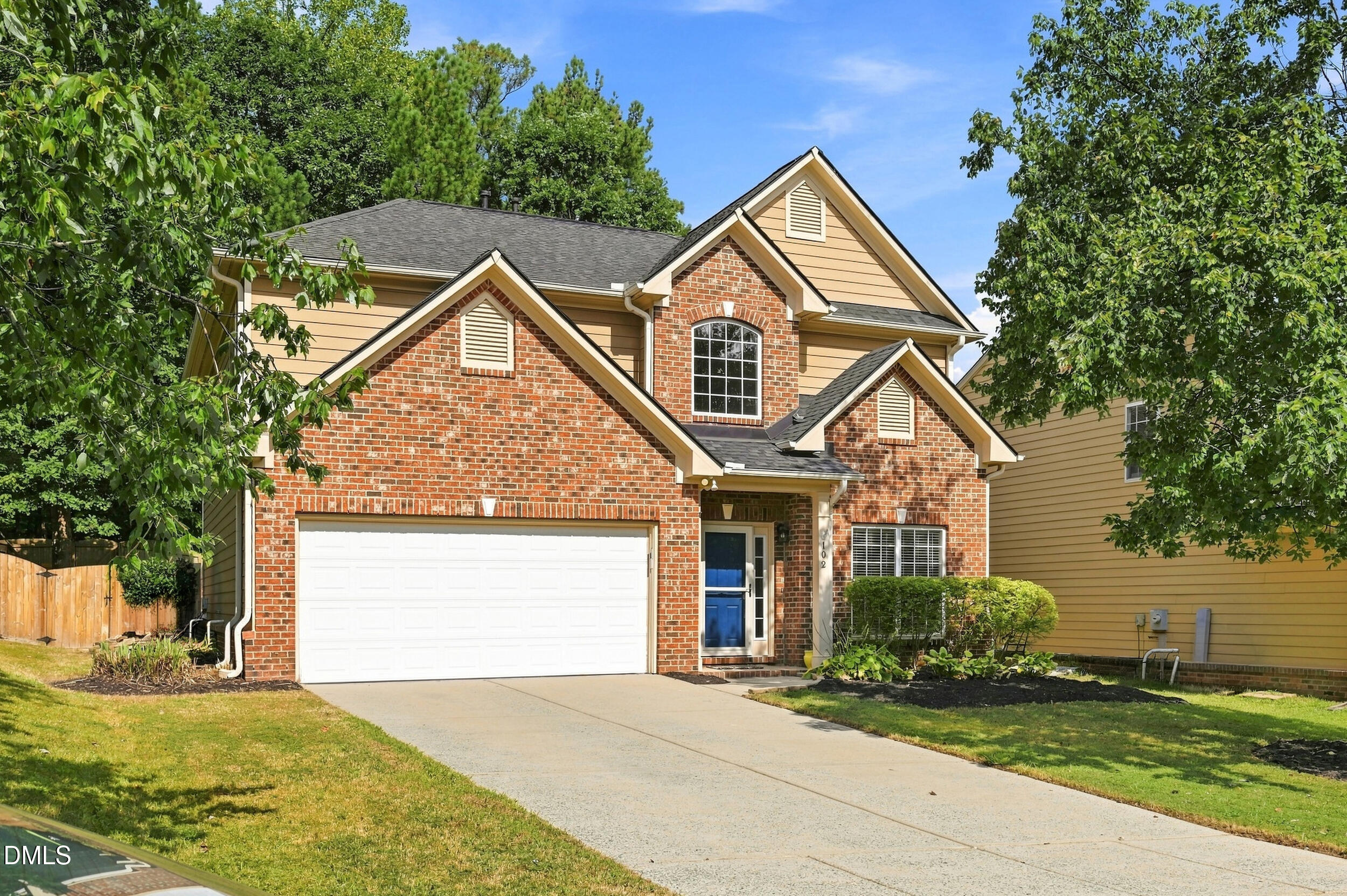 Brick-front suburban home with a white double garage door, blue entry door, and landscaped lawn.