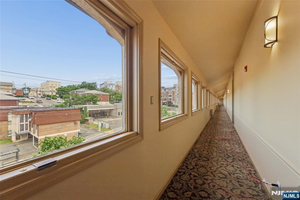 Long carpeted hallway with large windows overlooking nearby buildings.