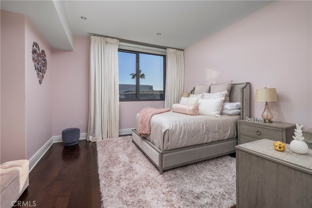 Pink bedroom with a gray upholstered bed, white curtains, and a plush pale rug.