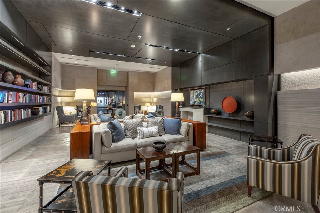 Furnished lounge with a gray sofa, striped armchairs, built-in bookshelves, and modern stone walls.