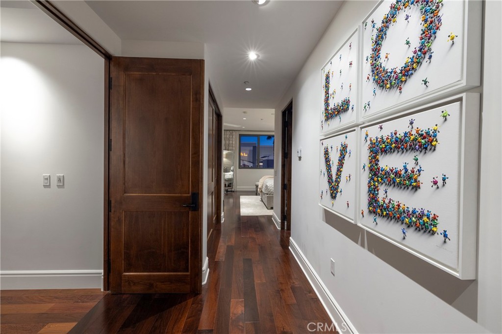 Hallway with dark hardwood floors, a dark wood door, and colorful framed LOVE artwork.