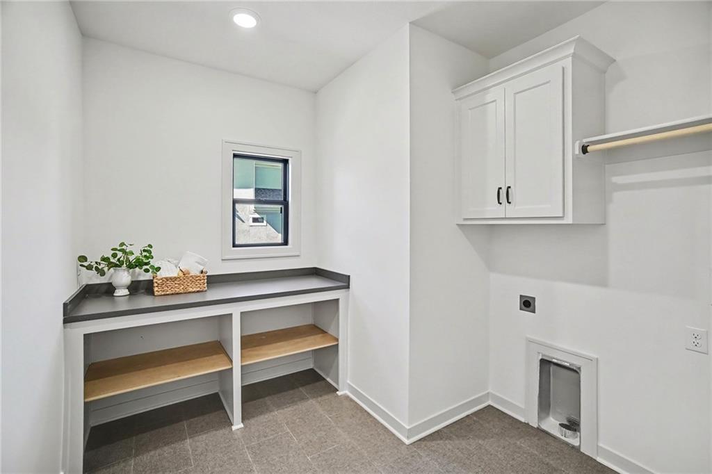 Utility room with built-in cubbies, dark countertop, wall cabinet, and a low pet-washing basin.