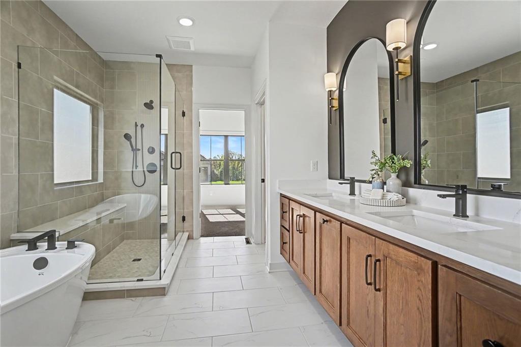 Bathroom with a glass shower, freestanding tub, and long wood double vanity.