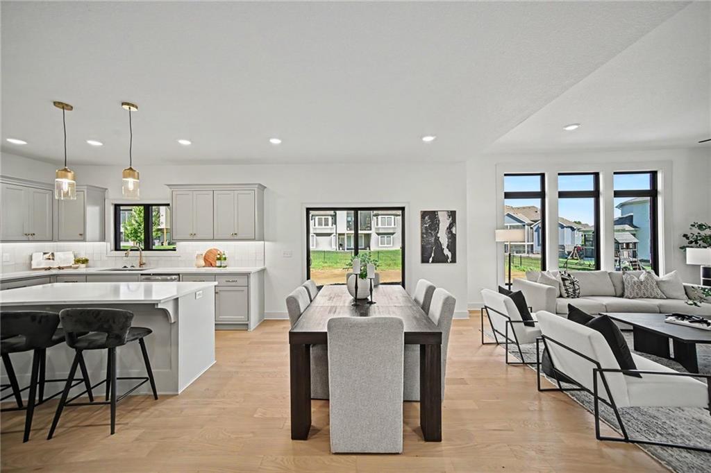 Open-plan kitchen, dining area, and living room with a large island and tall windows.