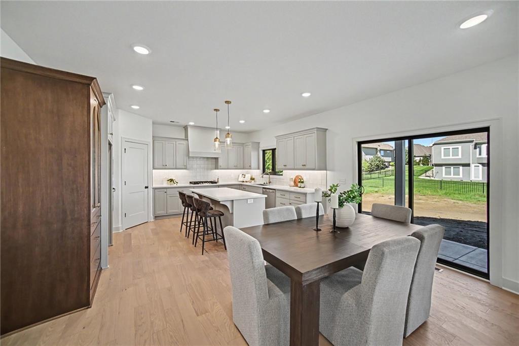 Open-plan kitchen and dining area with a white island, dark wood table, and sliding doors to the backyard.
